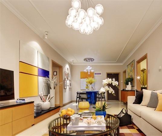 客厅以清新的柠檬黄为主色调，搭配使用亮丽的宝蓝色，两种显眼颜色的搭配点亮了纯白色的空间，彩色方格地毯和造型独特的吊灯都让室内充满活力。