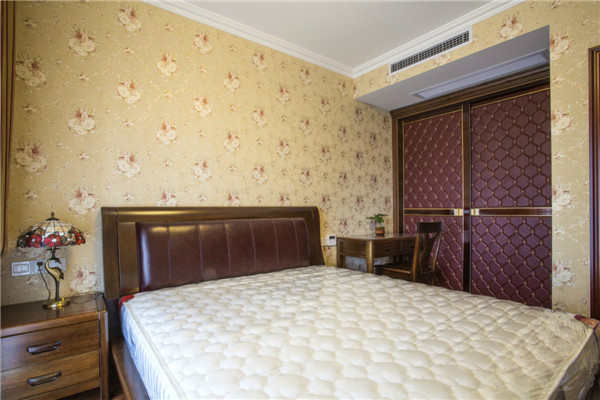 主卧室的墙面墙纸也是选用了具有富贵象征的牡丹花，深色的木色床给人的感觉比较的沉稳大气。
