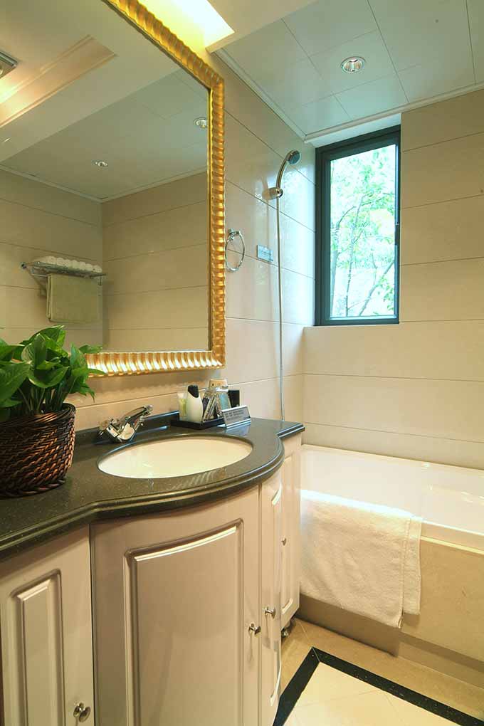 卫生间也充满了自然清透的气息。金色镜框在竹藤制装饰、绿色植物的搭配中和谐而更显精致。