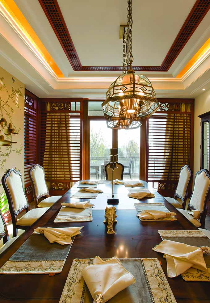 实木餐桌平滑的质感更好地映衬了食物的美好。吊顶投下的灯光将家人包围其中，倍显温暖。