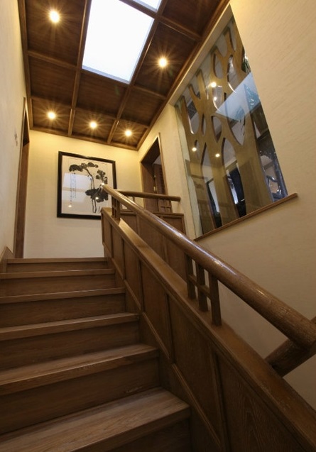 复式家居中总少不了连接上下层的楼梯，这个朴素的木质楼梯设计，虽没有复杂的点缀和装饰，却有着颇具古典韵味的典型气质。吊顶上的射灯按照一定的形状排列布置，营造出幽远意境。墙上的水墨画让空间有了艺术气息。