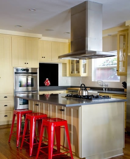 橱柜在颜色上的选择也要保持家居装修主题的统一，采用淡黄色的防火防潮板制作的橱柜，将客厅和厨房有机地联系在一起。流理台旁边鲜红色的椅子，能迅速吸引人的目光，给人以强烈的视觉冲击。