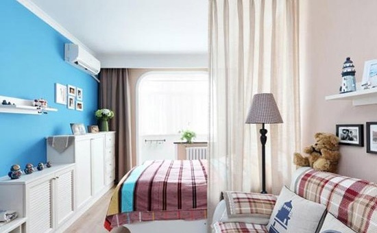 客厅与卧室只用了一扇纱帘来隔开，软隔断在保证隐私的前提下，也让空间具有更好的连通性。粉刷了蓝色墙漆的墙面显得活泼温雅，一排连续的储物柜让收纳有了足够的空间。