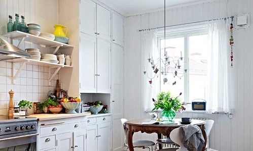 纯白色橱柜与白色墙面几乎串联成为了一体。半透明的纱帘减少了对外界光线的阻挡，使得厨房采光尤为充足。为了避免过于单调，设计师特地选择用绿色植物以及其他原木家具进行了装饰。