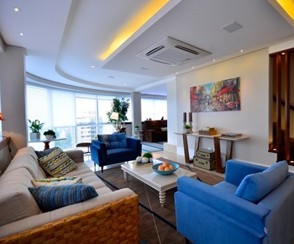 复式公寓的一楼客厅，以弧线延展开来，宝蓝色的沙发与黄色的天花板灯光相映成趣。大大的落地窗，最大限度的吸收了阳光，明亮了整个客厅。客厅与楼梯，用长木条隔开，显得新颖别致。