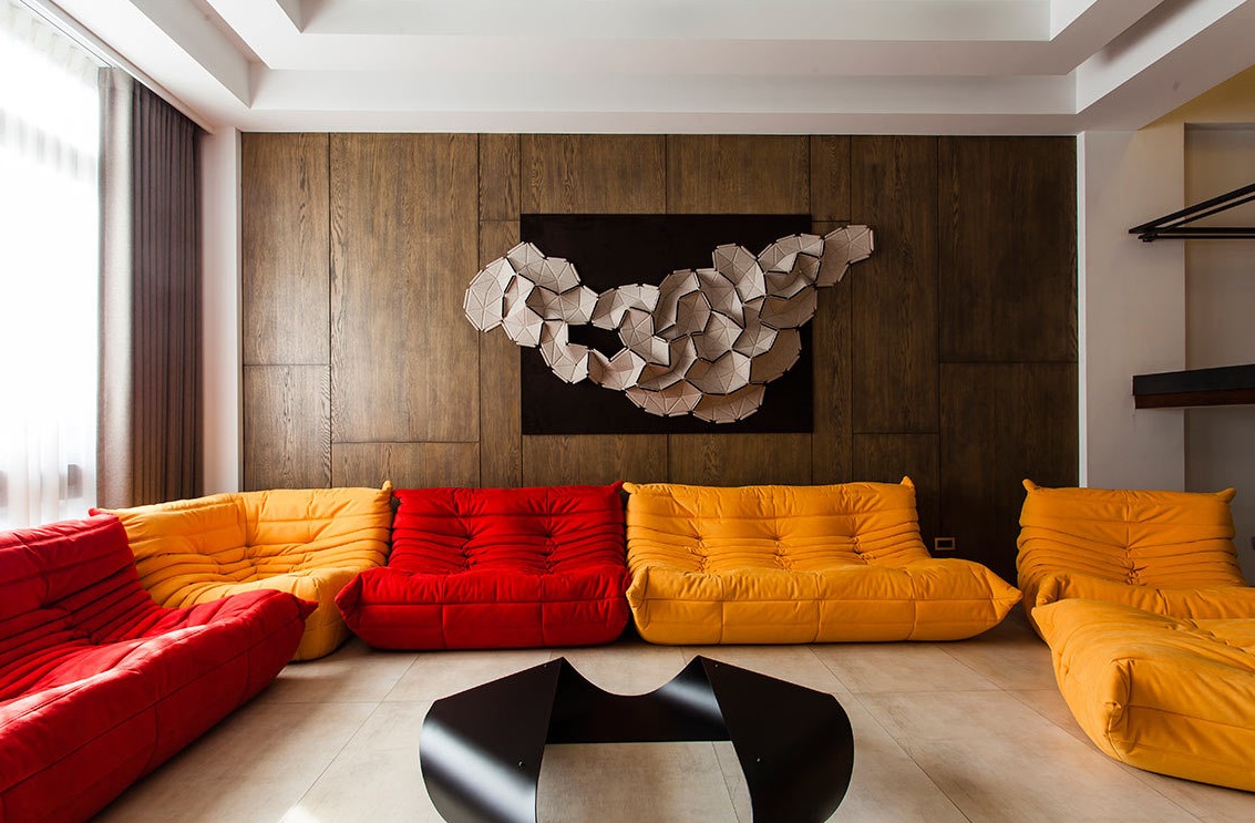 前卫立体的大型壁饰前端放亮色缤纷的造型沙发，呈现出了不羁的创意与无拘无束的生活风格。