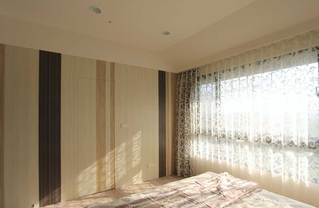 木质拼接成面的床尾主墙，以深浅的不同变化出不造作的自然质感，也将屋内的卫生间巧妙地隐于无形。