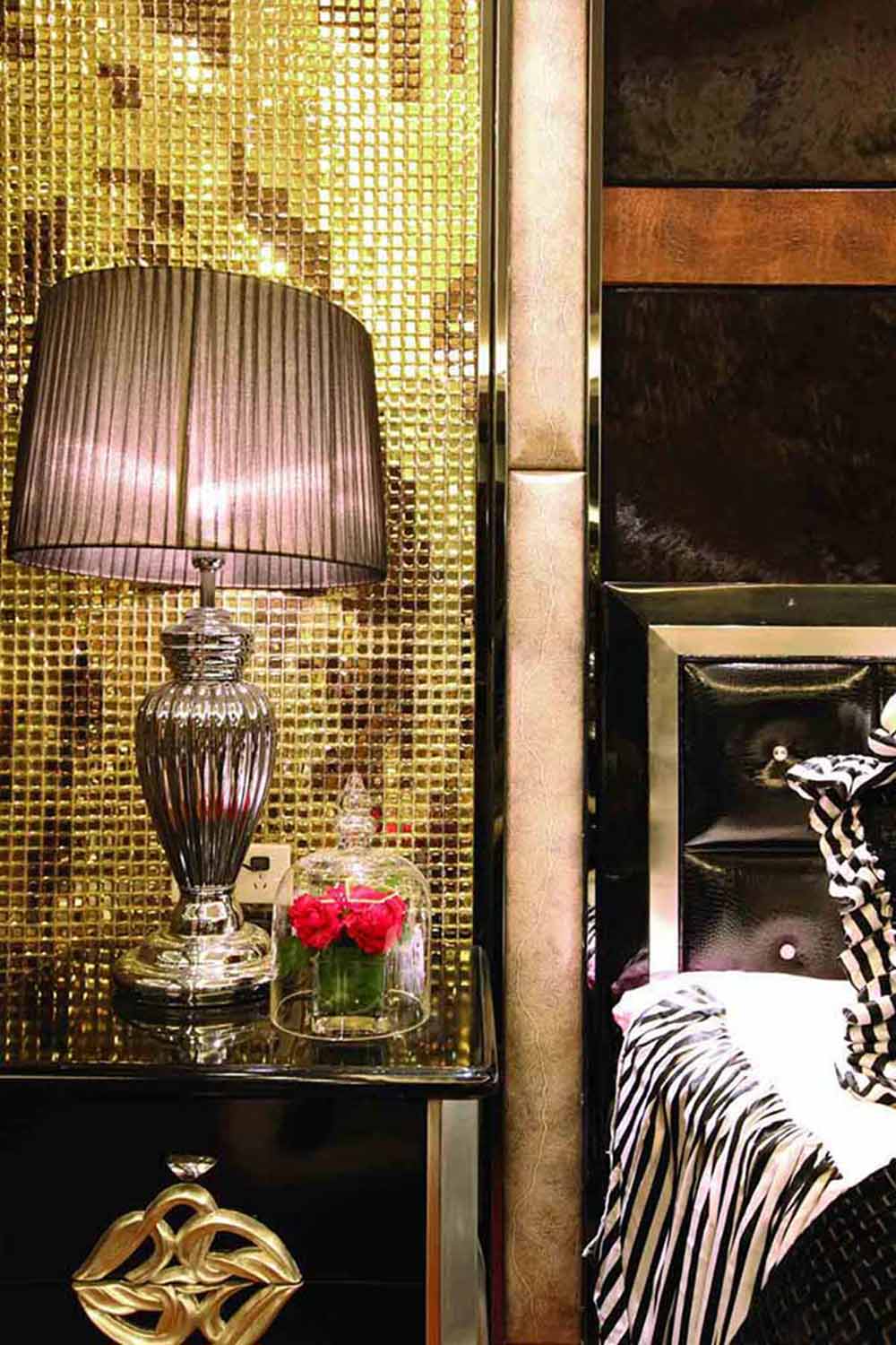 床头主墙采用金色马赛克铺饰，闪耀着高端生活的光芒。床头柜的精致装饰、台灯表面的金属质感也无一不凸显了设计师的用心。