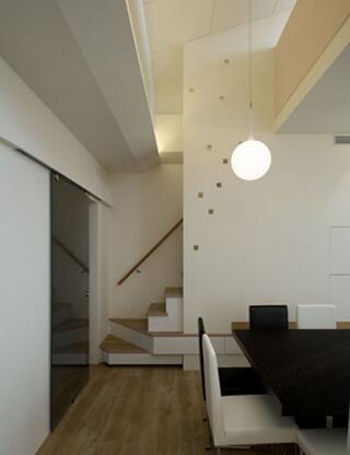 楼梯区域墙面镂空式的小方块装饰增加了空间内的灵动性。黑白餐桌用色简洁，与整体装修风格相符合。