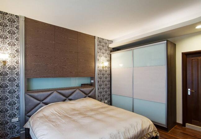 男主人卧室颜色风格沉稳低调，床头的两侧安排了黑白的图腾壁纸，维持了一贯的低调奢华感。