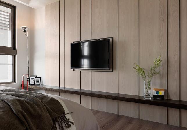 于主卧室内融入大量的木色元素增添了空间暖度，并于电视主墙上加入线条修饰，增添了立面的层次变化。