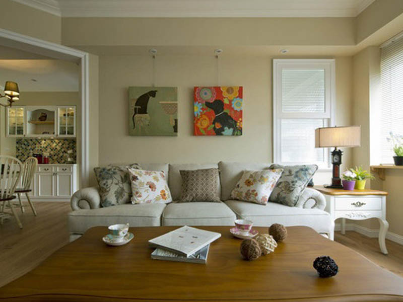 悬挂式壁画既能装饰墙面，又容易清洁打理。沙发选用偏向美式乡村风格的卷边沙发，放上小碎花靠枕。