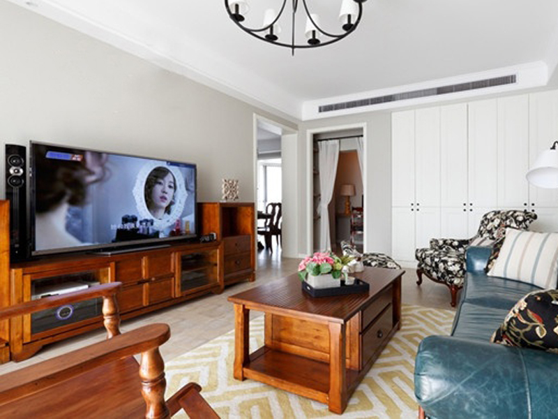 客厅不大，大致分成三块区域，一块是用白色柜子装饰的墙面，一块是木制造型电视柜，一块是用地毯分隔出来沙发休闲区。