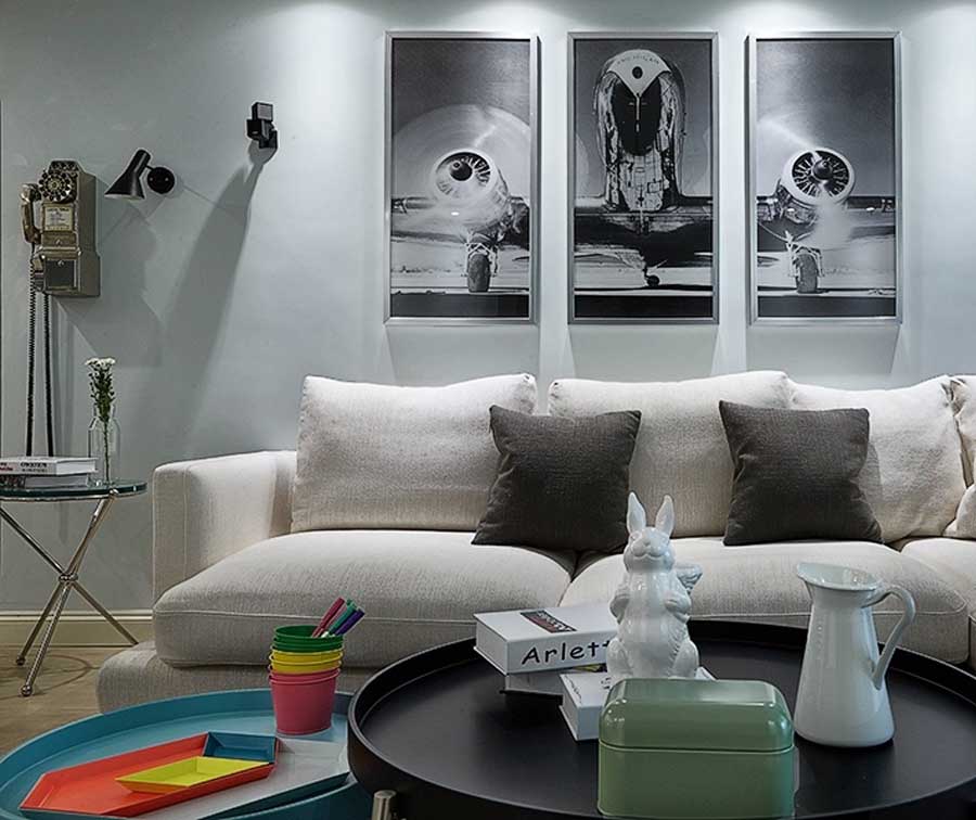  客厅选用灰白作为主色调，他们尤其喜欢沙发后的壁画。照片是她在一个飞机展览上拍的。