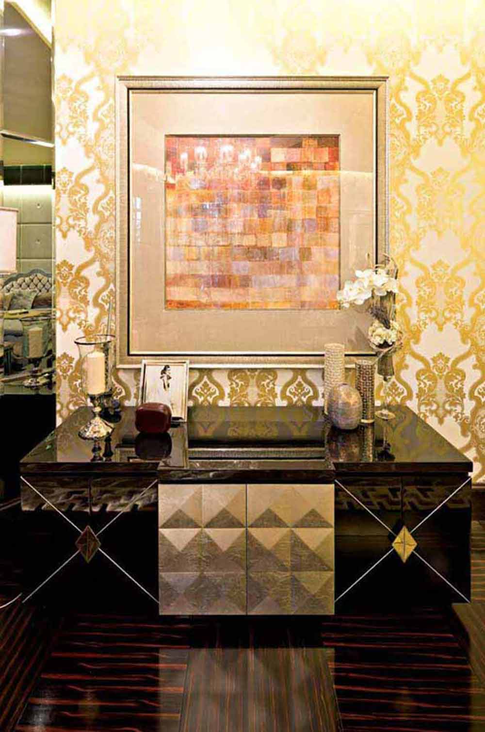金色壁纸图样精美，墙壁上的装饰画内容散发着现代抽象的艺术风格，下方以造型设计精致而实用的收纳柜做搭配，高雅的生活品味由此凸显。