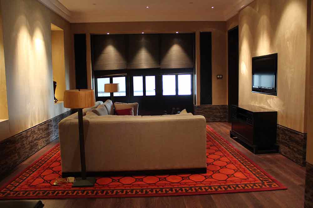 客厅亮红色的地毯为该区域铺陈出了主要的基调。灯光的运用营造了柔和为温馨的氛围。