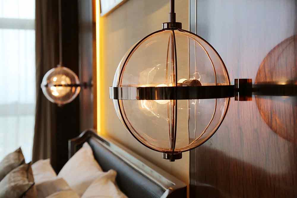 床头造型别致的吊灯模仿“灯笼”的造型，以玻璃和金属元素加以装饰，实现了古典和现代的交融。