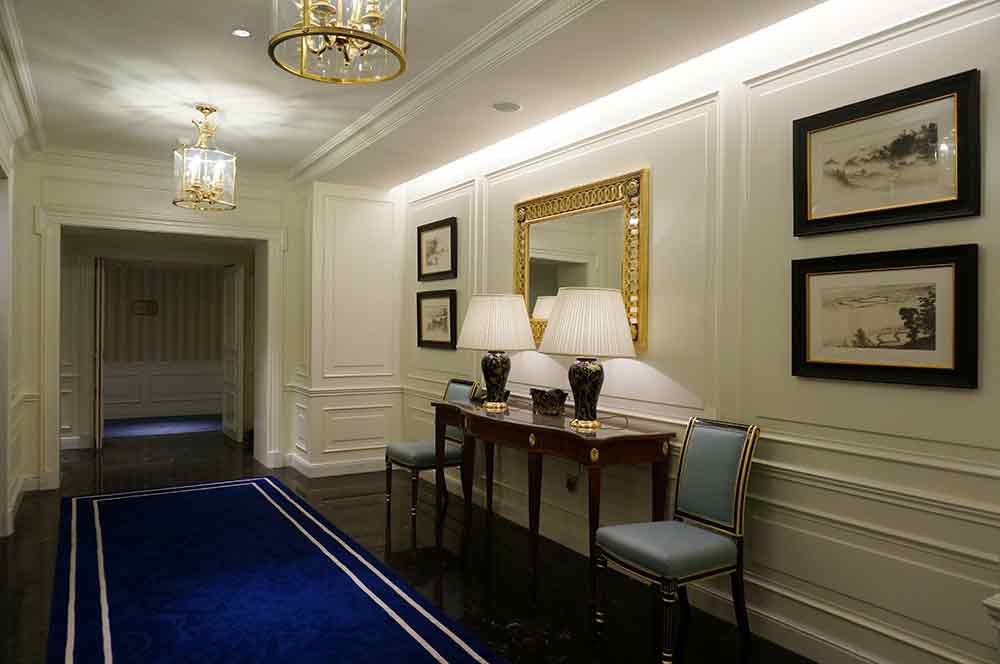 大块宝蓝色的地毯将高贵的气质凸显了出来，墙面对称式的装饰设计将过道区域也设计成了一处极佳的休憩区域。