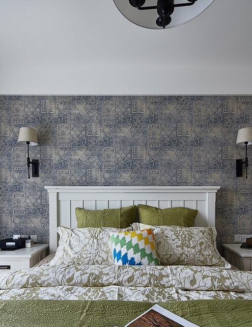 主卧的床头墙下半部分以精美的雕花壁纸铺饰，与绿色调的床品协调相称，在冷色系的设计中凸显了轻松随性的生活个性。