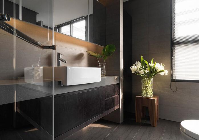 浴室以深色的材质作为视觉重点，搭配大面具有空间放大效果的镜面元素，塑造出了沉稳而温馨的私人空间环境。
