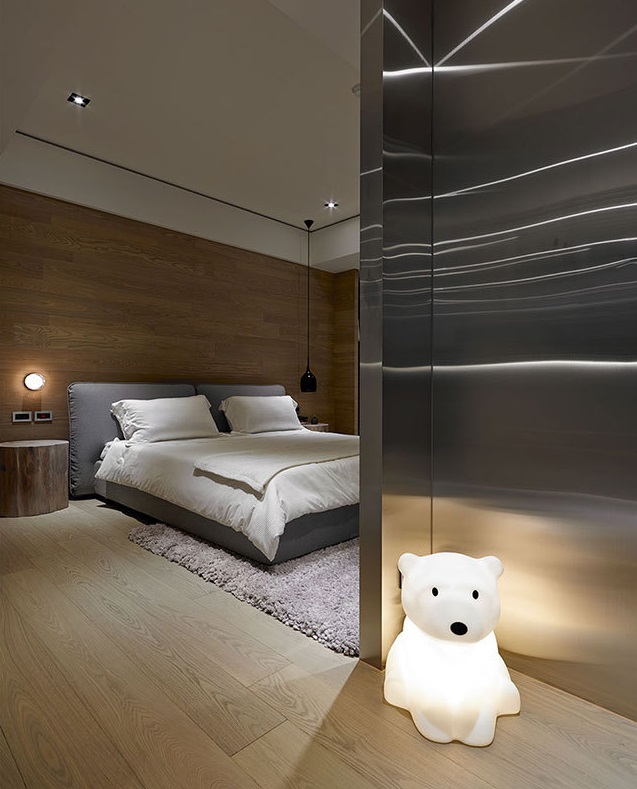 卧室以木作墙面和不锈钢墙面作为视觉重点，形成了自然感与工业风、温软与硬冷的对比，带出了独特的冲击美感。入门处可爱的小熊造型灯将纯净的氛围发散至全室。