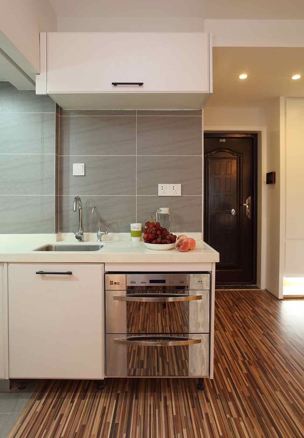 小巧的厨房以灰色的瓷砖铺贴墙面，耐脏且易打理。地柜加吊柜的设计满足了基本的收纳需要。