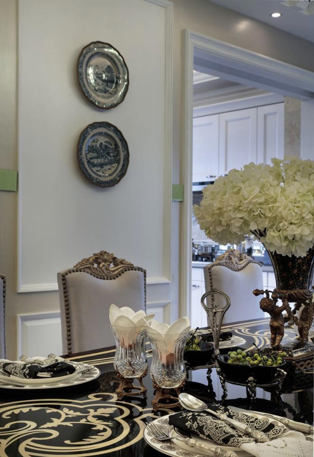 黑色祥云图案装饰大理石餐桌，显得深沉高贵。玻璃酒杯里的白色花朵让就餐环境不会过于冷漠。