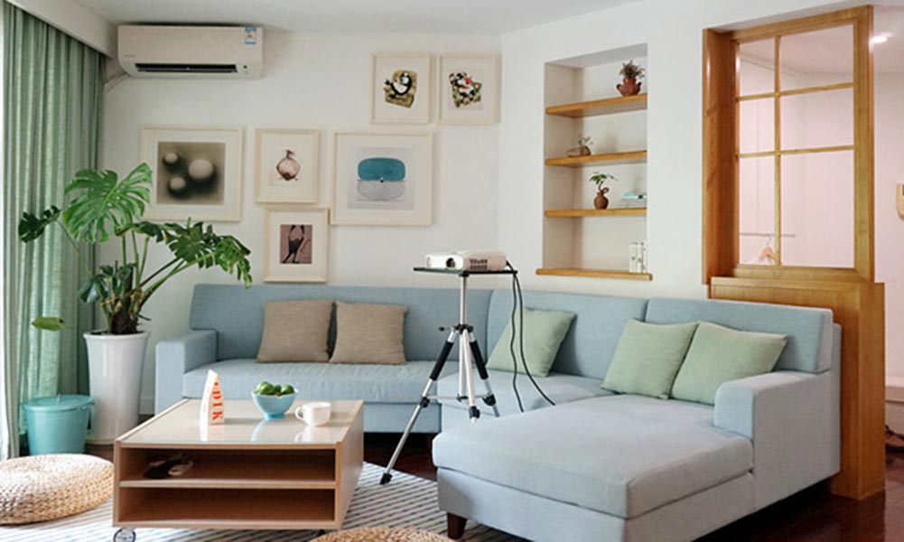 沙发的形状与空间格局相称，背景墙面一面设计为照片墙，另一面则用木质元素设计为收纳展示层板和隔断，凸显出了小资的精致审美。