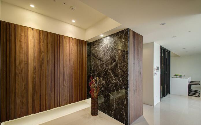 玄关处以天然胡桃木皮铺陈，搭配大面黑色大理石墙面让空间更具现代质感。