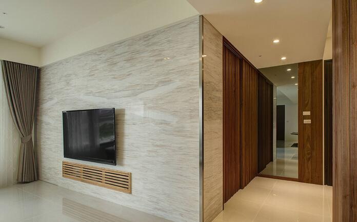 从玄关处转折延伸的电视墙，以精致纹理的木纹大理石铺陈，简洁的视感让人视觉舒适。