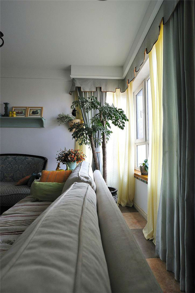 沙发与窗户腾出一段距离，窗边一盆大型绿色植物生长的很旺盛。