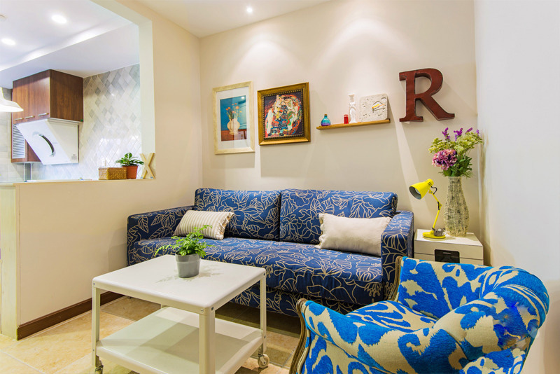 蓝色花饰沙发搭配素色靠枕、小几，以绿植、鲜花点缀，让客厅颇有趣致、生机勃勃，活泼的色彩对比彰显出优质美感。