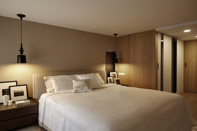 床头两边点缀美丽吊灯，右侧巧妙的修长开窗处，隐约可以望见客厅景致。
