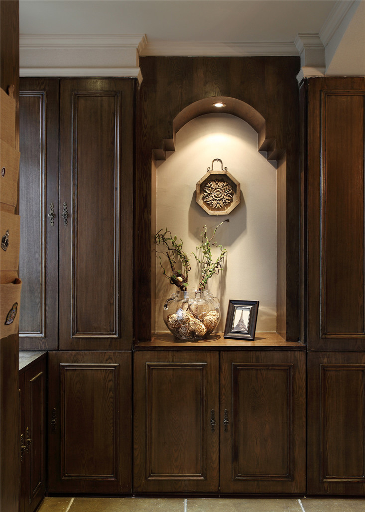 入户处法式风格尽显，连续式的深棕色木质橱柜，给浪漫更多的储藏空间。挂壁式的金属挂件誓将复古进行到底。