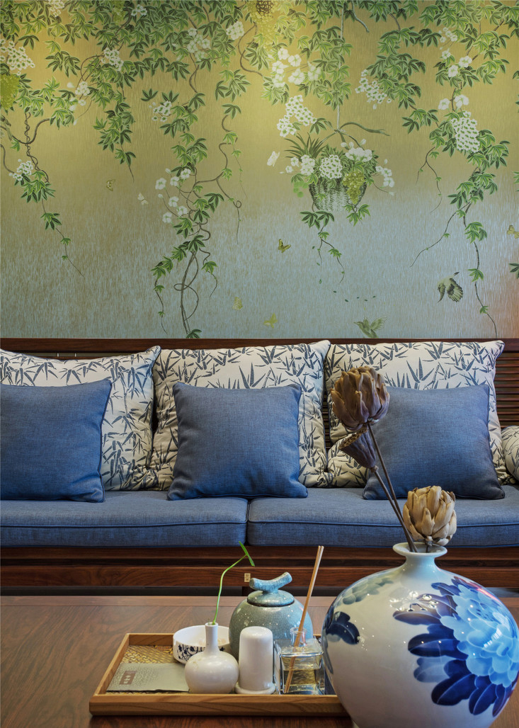 抱枕上青花勾勒的竹子与桌上一色瓷器交相辉映。背景墙上的葡萄藤凌乱交错着两个时代。
