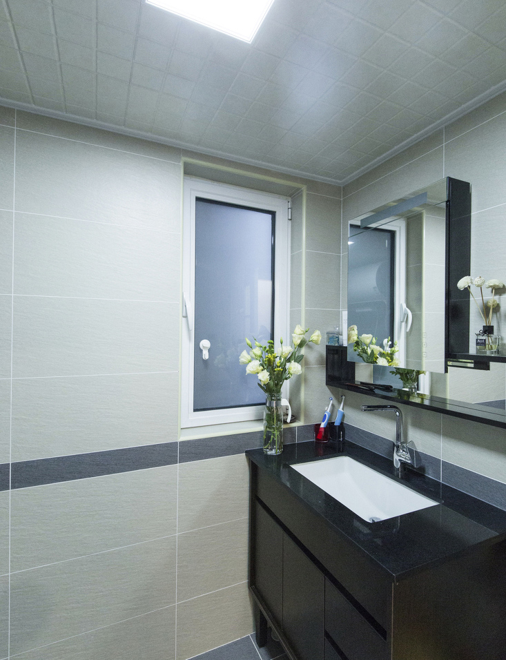 洗手间用大块素色墙砖营造低调，简单的镜子设计很“职场”。