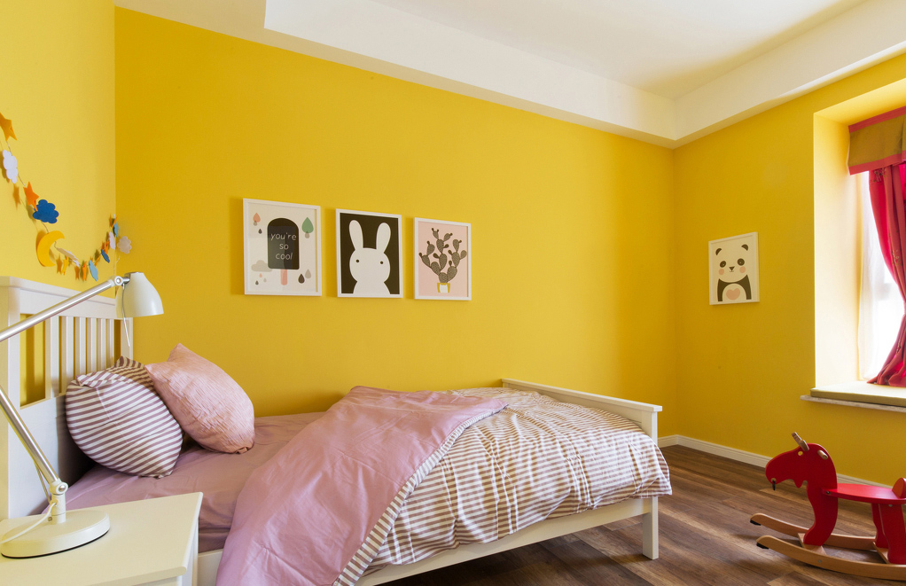女儿房则用大面积黄色墙面加挂画的设计，让空间变得灵动。小木马摇曳着，载着小主人去往童话世界。