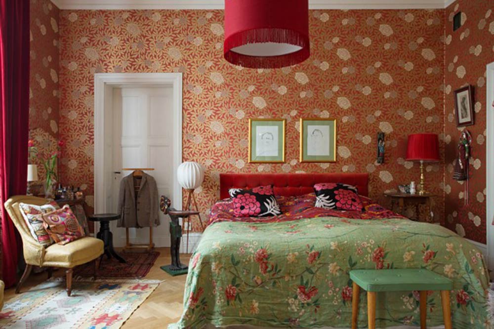 房间里的红色碎花壁纸与绿色碎花被套和谐相处，并不冲突，共同营造温馨浪漫的氛围。