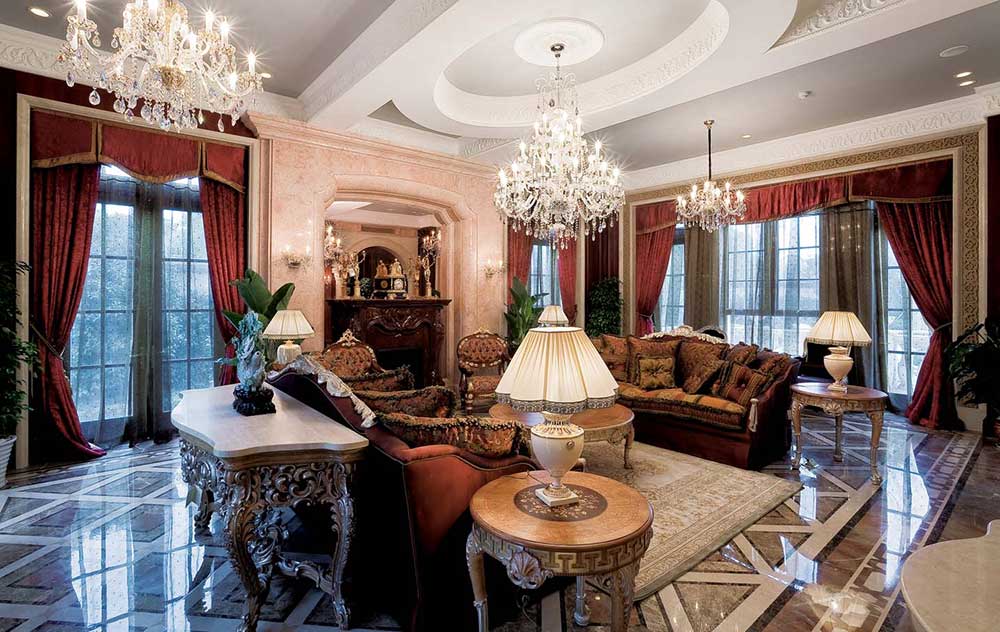 客厅吊顶安装了三座水晶灯，光线洒在暗红色布艺沙发和精美浮雕装饰的家具上，给人一种庄而不重的奢华感。
