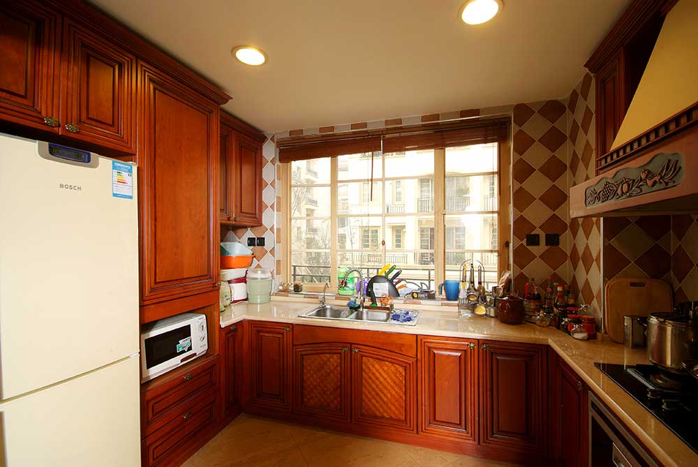 厨房的墙面是橙黄色瓷砖，与同色橱柜融为一体，温馨雅致。