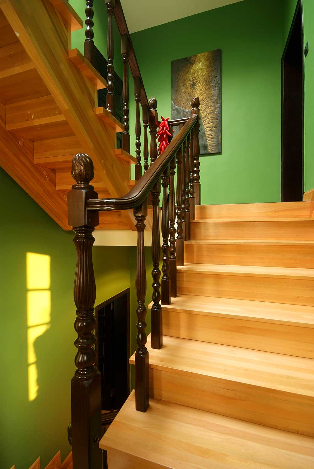 清新裸色的木质楼梯与深咖啡色的扶手形成对比，蜿蜒通向二楼。