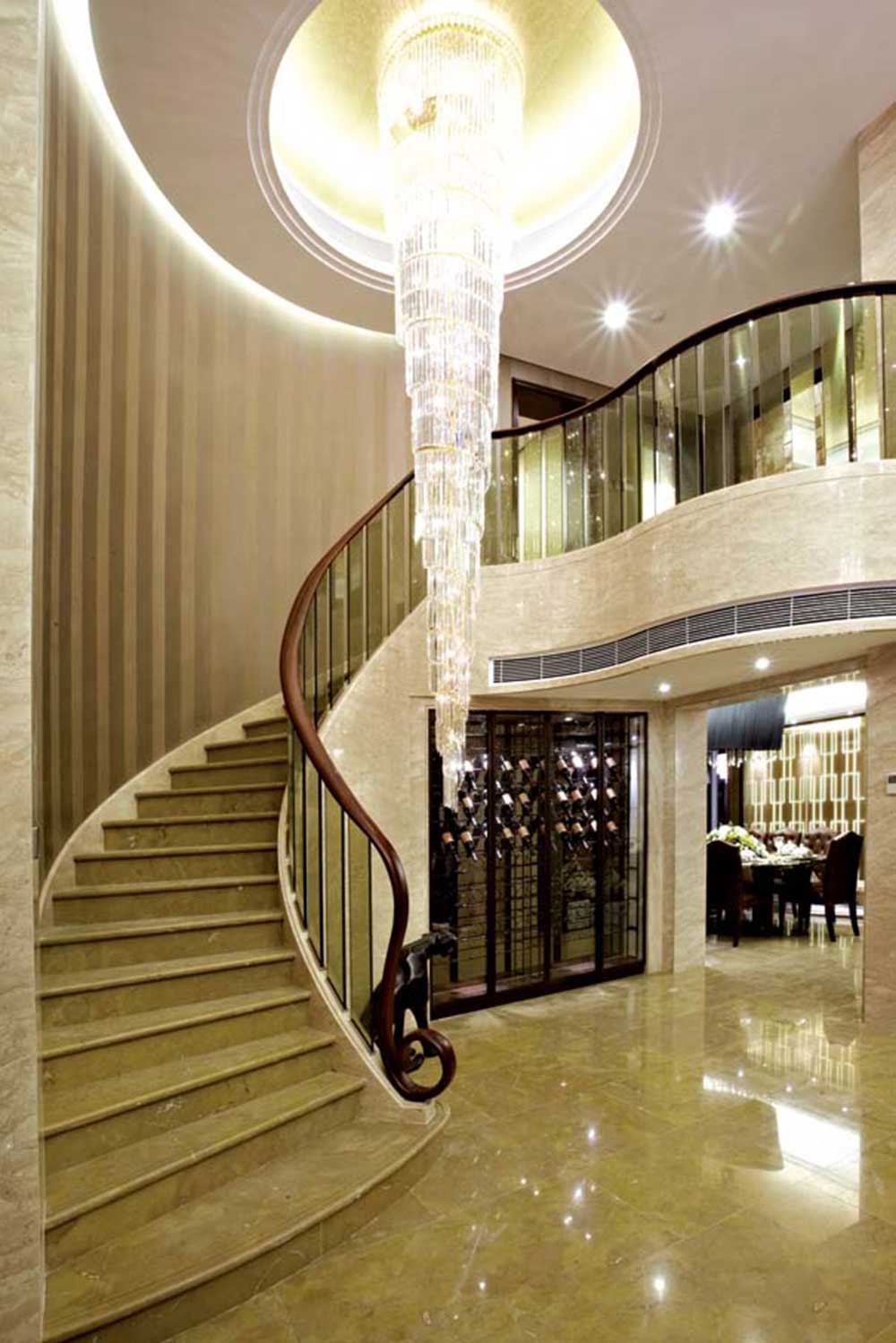 楼梯蜿蜒通向二楼，流线型木质扶手给人温柔的感觉，垂坠的大型水晶灯则给人闪耀的美感。