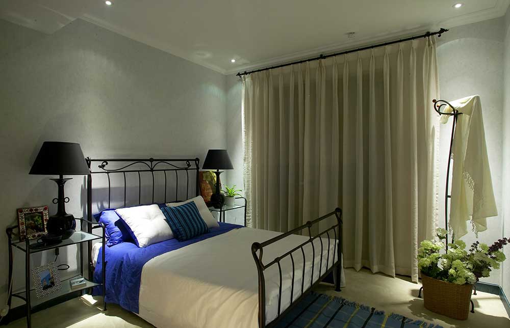 卧室省略了吊灯设计，明亮的射灯成了卧室的主光源。铁艺的床架和麻质的窗帘，带着美式风格的粗犷设计。