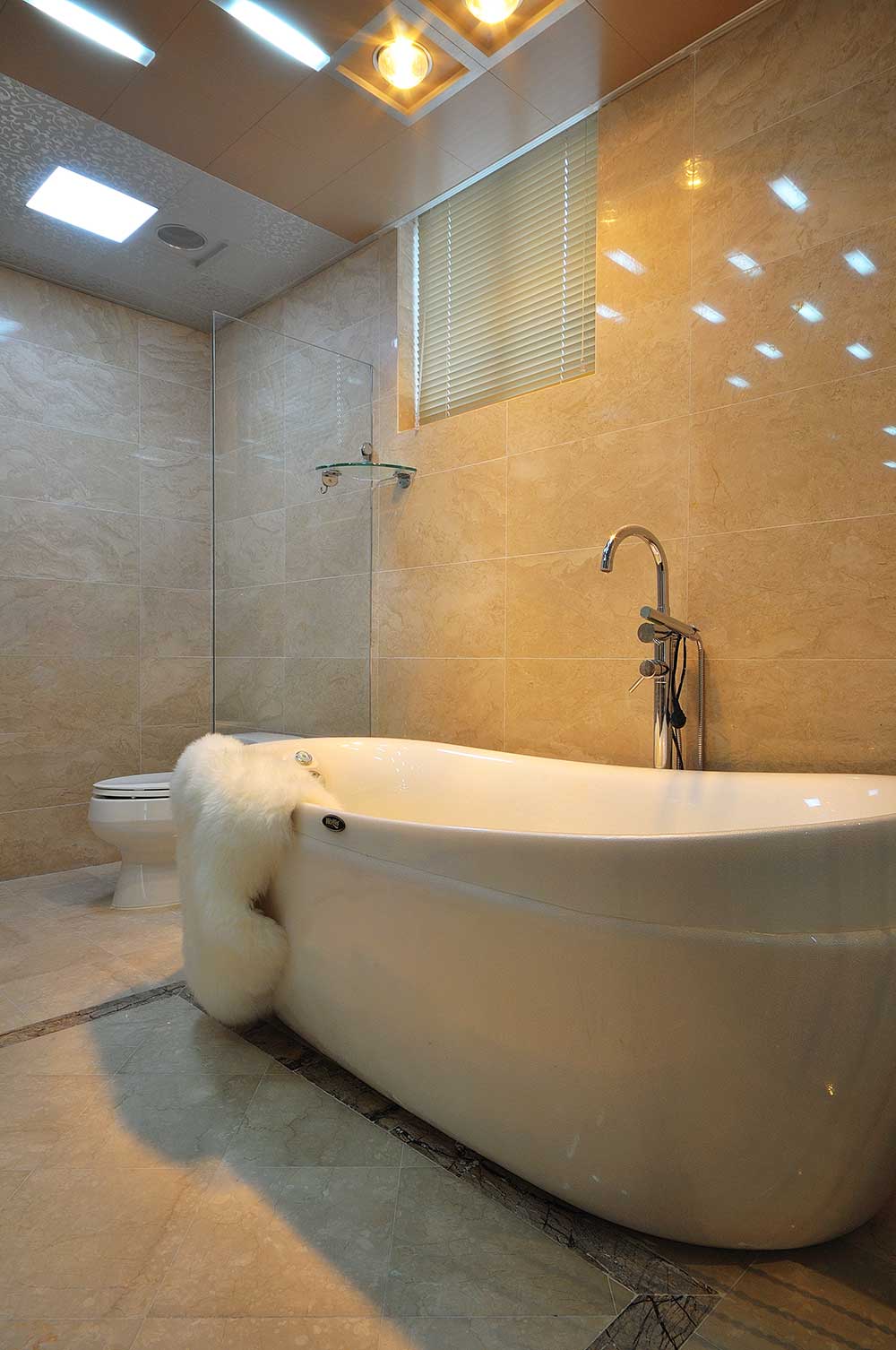 卫生间装修的简单一些，一个浴缸摆放在卫生间的中间，简约大方。整个卫生间吊顶的灯光也非常简约。