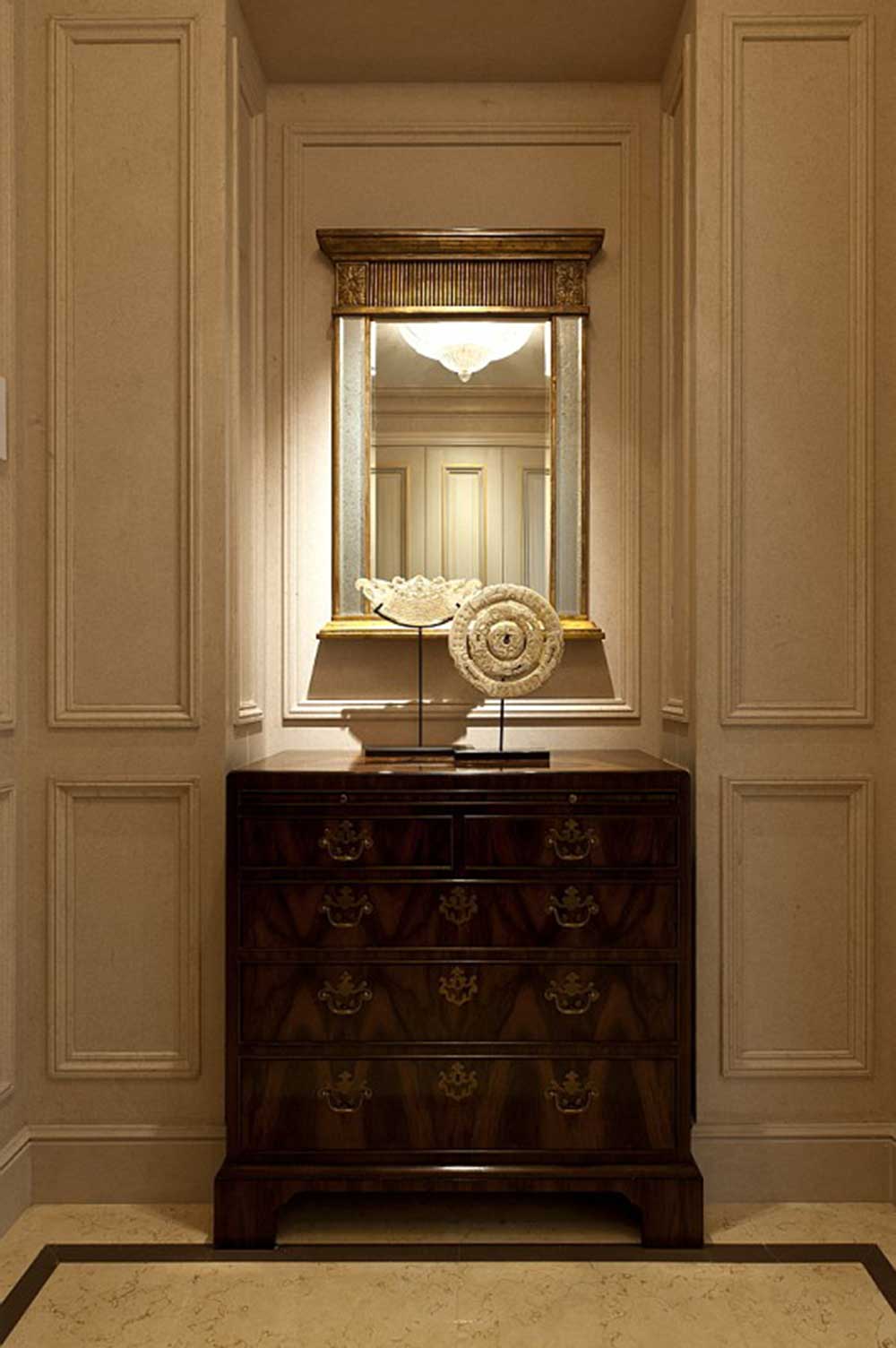 入门玄关处的装饰柜摆放的很端正，装饰柜柜门拉手充满了古典韵味，一面镜子装饰在柜子之上，增加了空间。