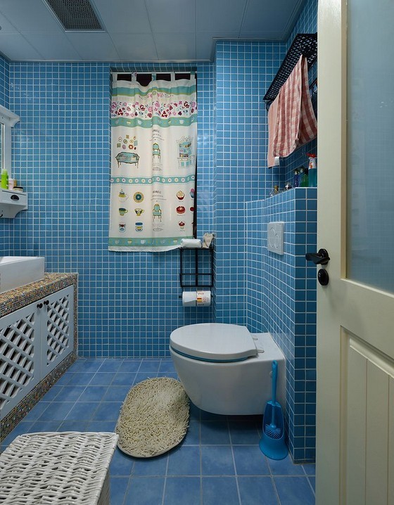 地中海风格的卫生间，蓝色格子铺满了整个地面和墙面，更巧妙利用了挂壁马桶上方的储物收纳空间。