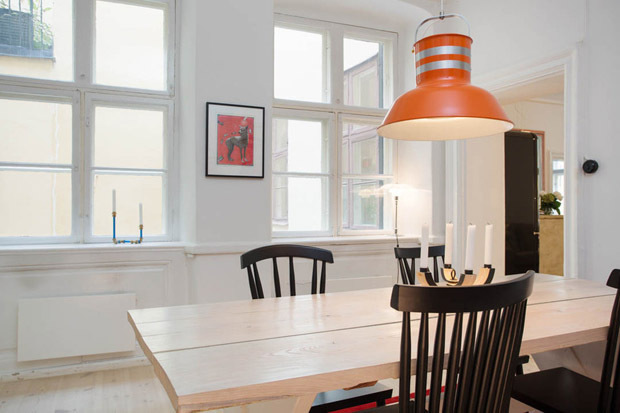 浅色的原木餐桌，与偌大的两扇平门窗相互辉映，橘色吊灯散发出耀眼光芒。