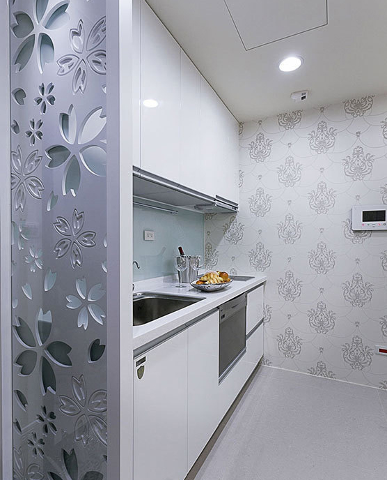 银光墙纸延续到对面的灰色雕花板，作为入口与邻近厨具之间的分界，达到缓冲视觉的功能。