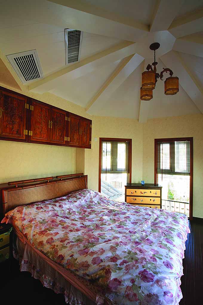 次卧同样延续了一致的风格，藤制床头和雕刻墙柜呈现出历史的厚重感。