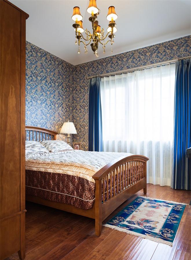 次卧是蓝色的木色的结合，墙面蓝金色的花纹墙纸，贵气十足，搭配床尾蓝白相间的小块地毯，仿佛行走在意大利托斯卡纳的街头。